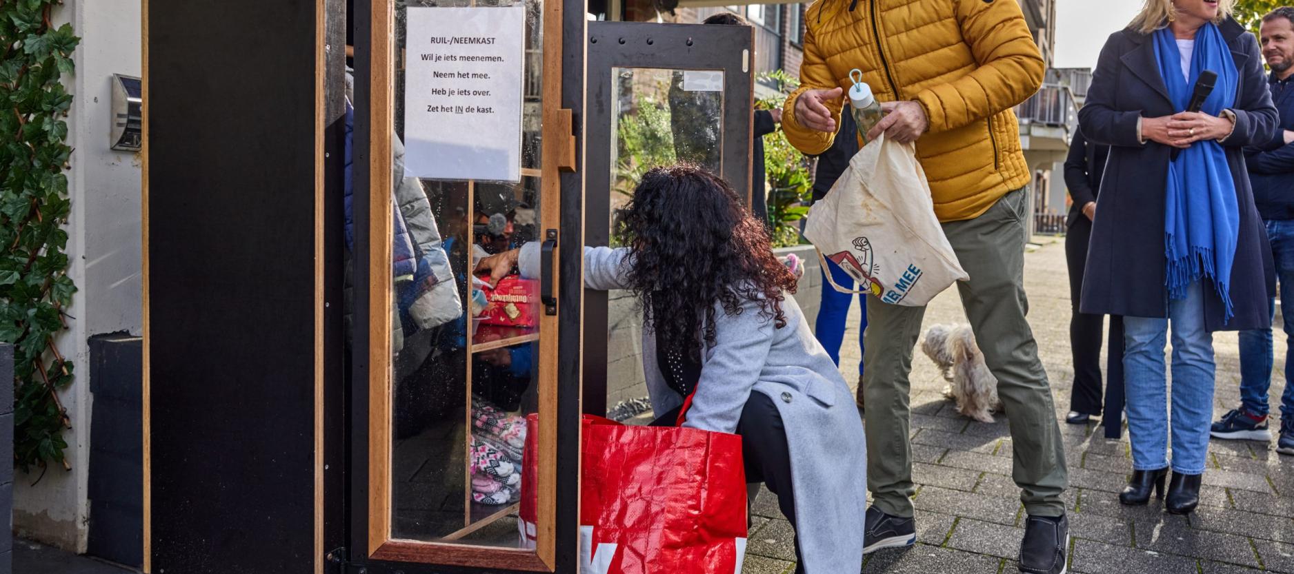 Mensen plaatsen spullen in een weggeefkast